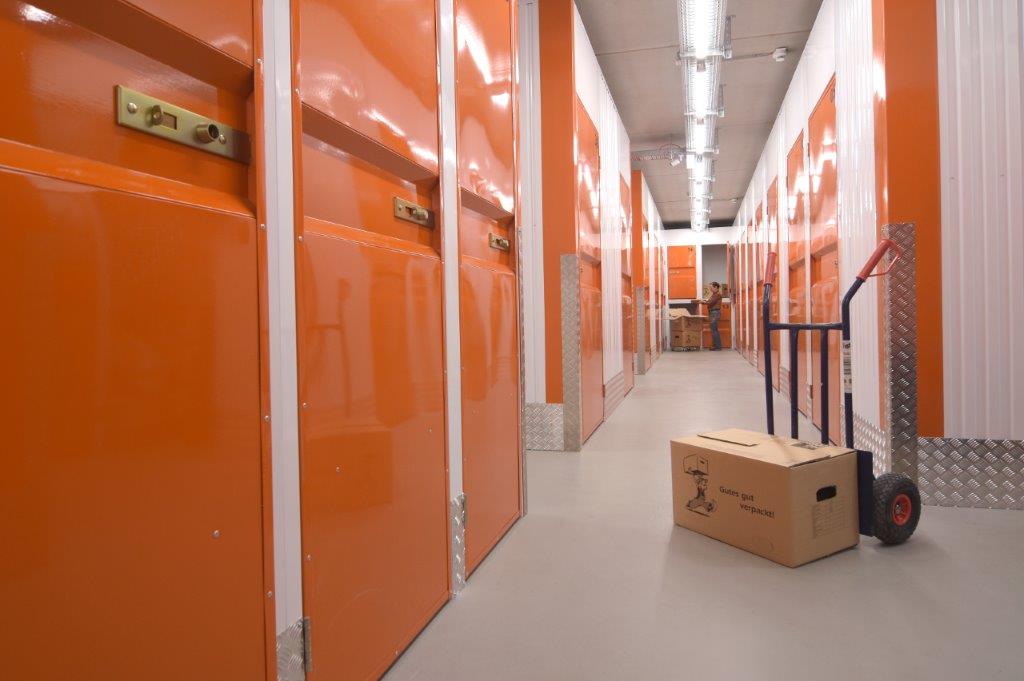 KW-Box Bremerhaven – Innenansicht Flur mit orangenen Lagerboxen und Sackkarre